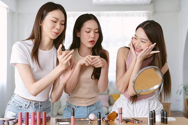 istock Happy beautiful three young Asian women doing makeup and testing lipstick on together in living room. Korean influencer girl with make up cosmetic routine at home. Makeup, friendship skincare concept 2213007929