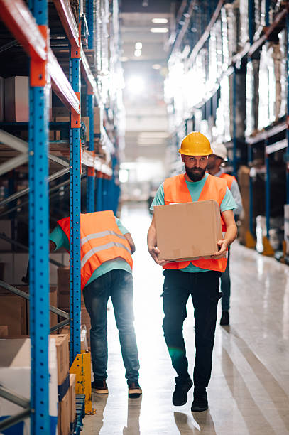 istock Warehouse workers carrying cardboard boxes in distribution center 2213010578
