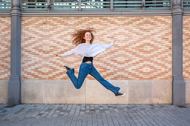 Beautiful young woman jumping with an umbrella outdoors in autumn.