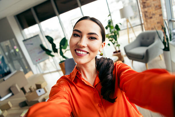 istock Confident young entrepreneur taking a selfie in a modern workspace, showcasing a vibrant and professional ecommerce environment. 2213012688