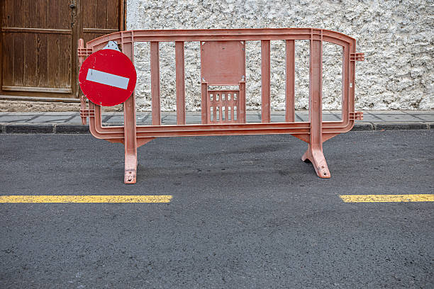 A damaged safety barrier with broken concrete base lying on a gravel surface at a construction or industrial site, showing impact damage, safety issues, and repair needs.