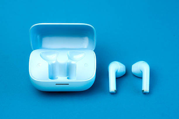 istock A pair of modern wireless earbuds placed next to an open charging case on a blue background. A sleek, stylish, and compact audio accessory perfect for daily use, music, and calls. 2213013792