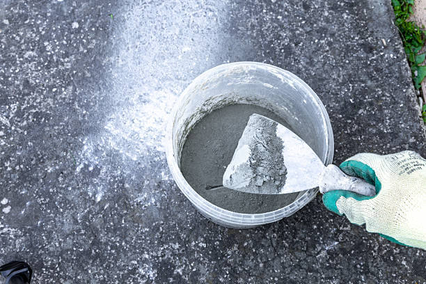 istock Mixing glue and mortar for gluing tiles on a terrace, container on a concrete sidewalk 2213014477
