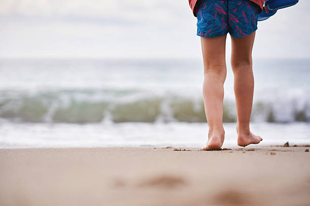 istock Close-up of barefoot child walking on sandy beach 2213017944