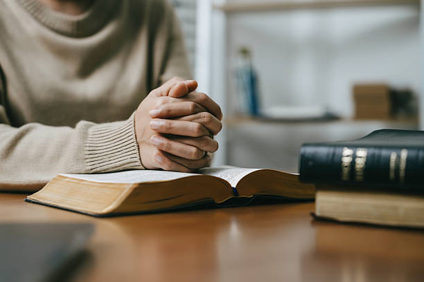 Christian pray and worship god with belief and spirituality. Hand praying and praise with the holy bible in church. young woman prayer confession sin for seeking peace relationship in Jesus christ stock photo