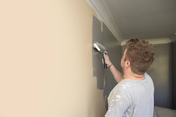 istock Young, self employed and skilled Painter & Decorator overcoming the disability of having one hand, decorating a domestic living room with a roller 2213021707