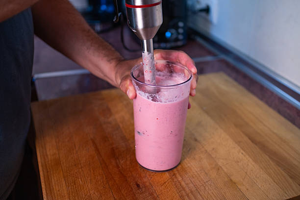istock Person blending a colorful smoothie in a kitchen using a hand blender 2213022322
