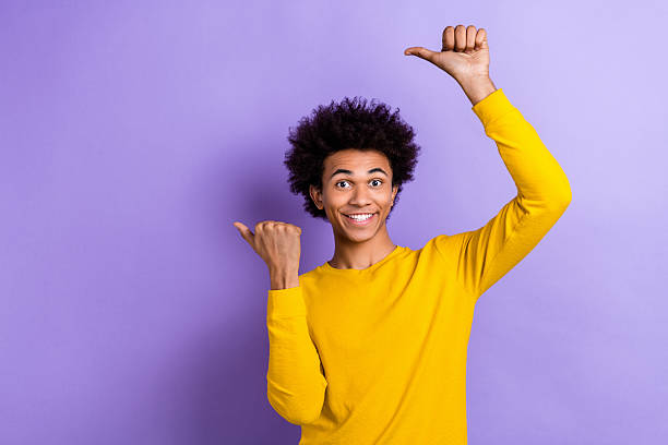 istock Photo of optimistic funky nice guy dressed yellow long sleeve indicating at discount empty space isolated on purple color background 2213022604