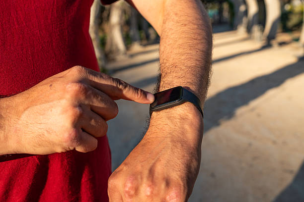 istock Person interacting with a smartwatch while walking through a sunlit park during the late afternoon 2213022949