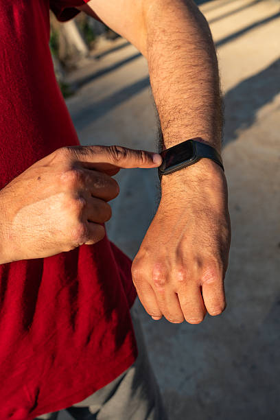 istock Man checking smartwatch while walking in the evening sunlight along a pathway in a quiet neighborhood 2213023159