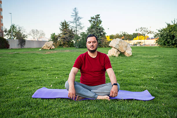 istock Man practicing meditation in a park surrounded by greenery during a clear day 2213024379