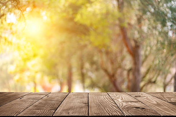 Empty wooden table with lush foliage at background. Ideal for product montage