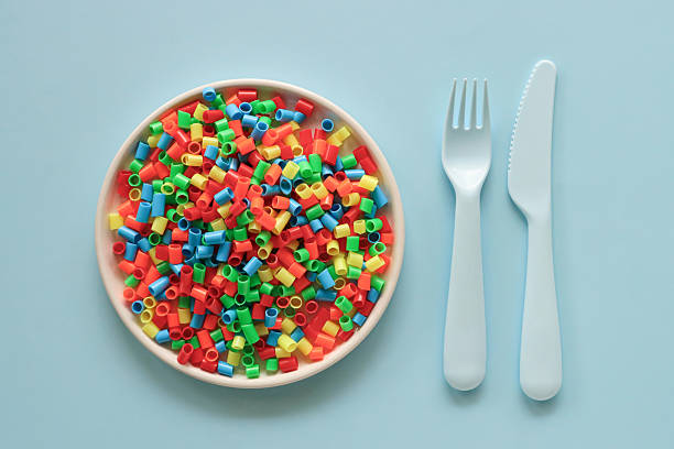 Stock photo showing close-up, elevated view of plate containing a heap of microplastics. Microplastics can measure between 1 micron to 5 millimeters and are insoluble in water, unfortunately, they can leak harmful chemicals which can contaminate air, water and food and so cause harm to the health of the environment and human health. Food contamination and microplastics concept.