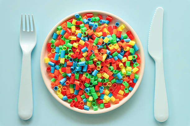 Stock photo showing close-up, elevated view of plate containing a heap of microplastics. Microplastics can measure between 1 micron to 5 millimeters and are insoluble in water, unfortunately, they can leak harmful chemicals which can contaminate air, water and food and so cause harm to the health of the environment and human health. Food contamination and microplastics concept.