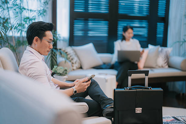 istock Asian Business Traveler Using Smartphone in Modern Lounge Area 2213026749