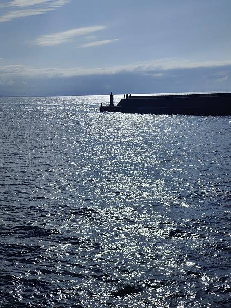 istock People walking on breakwater with lighthouse in background on sunny day 2213029225