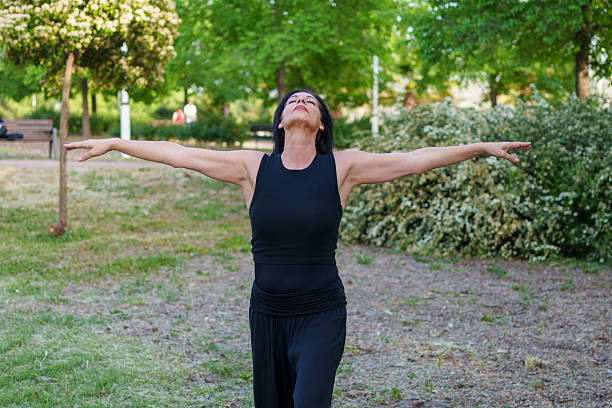 istock Mature woman practicing yoga in a peaceful park 2213030990