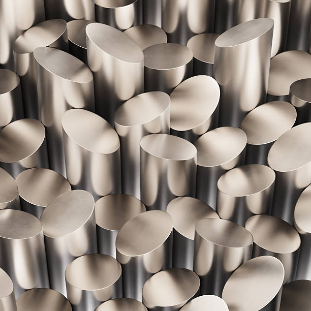 A CGI-rendered composition of circular metal cylinders, each cut at an angle to create slanted top surfaces. The rods are densely packed, their brushed metallic finish reflecting warm light. The pattern conveys industrial precision, balance, and repetition, referencing concepts in metallurgy, manufacturing, and material processing.