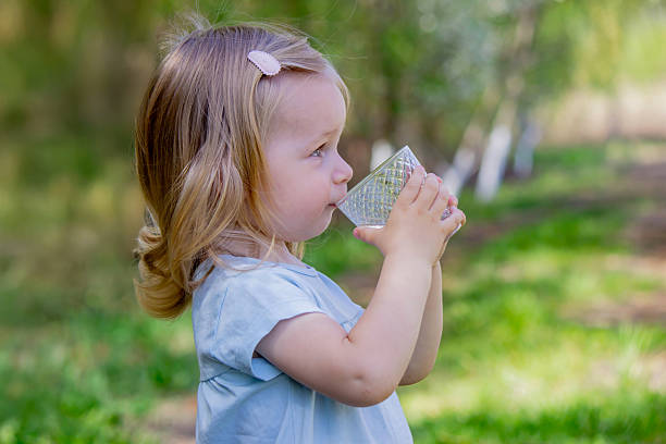 little girl drinking water from a glass.