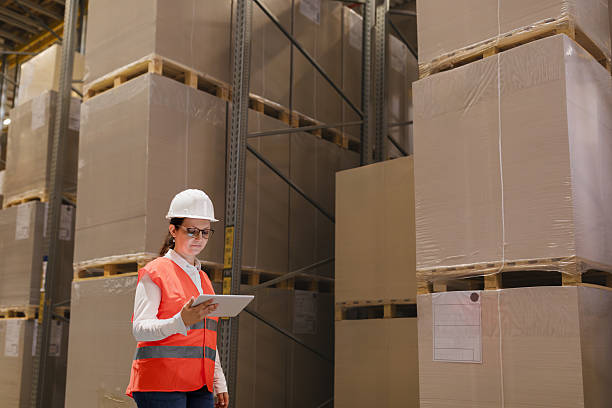 istock Female worker standing next to large stack of boxes in warehouse. 2213035170