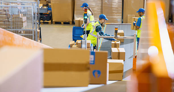 istock Workers in Logistics Terminal Loading Cardboard Boxes and Parcels with Goods onto a Conveyor System. Men and a Female Maintaining the Flow of Products for International Trade 2213036764