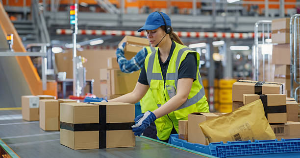 istock Young Diverse Workers in Logistics Terminal Loading Cardboard Boxes and Parcels with Goods onto a Conveyor System. Male and Female Maintaining the Flow of Products for International Trade 2213037591
