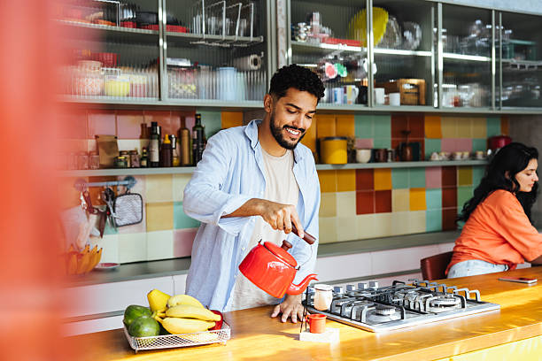 istock Man pouring tea in a cozy colorful kitchen while preparing for breakfast 2213038232