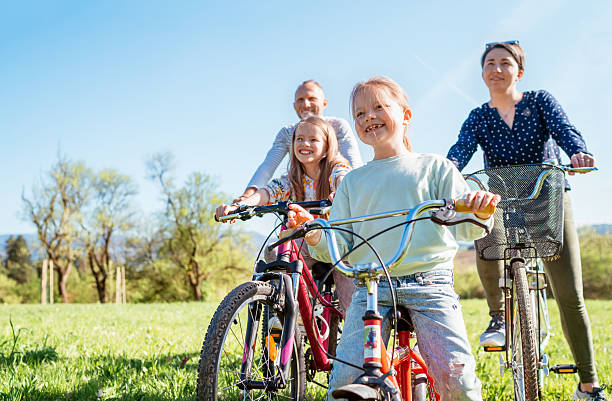 Happy family spending time together outdoors, riding bikes on a beautiful autumn day in a park