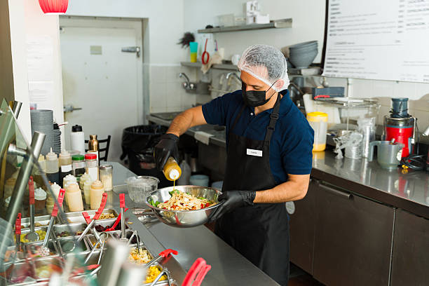 istock Restaurant worker pouring dressing on fresh salad at salad bar 2213038739