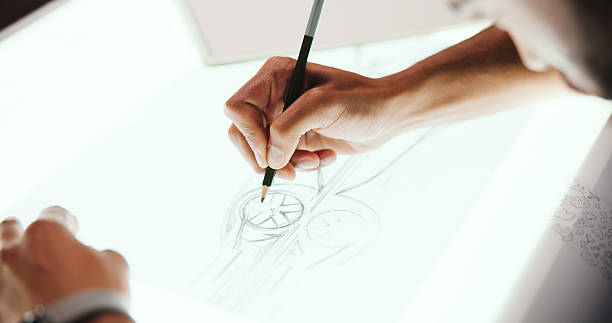 istock Person, hands and designer with drawing for car prototype, modeling or graphic design on light table. Closeup, mechnical engineer or digital sketch with 2D vehicle, blueprint or automobile project 2213043462
