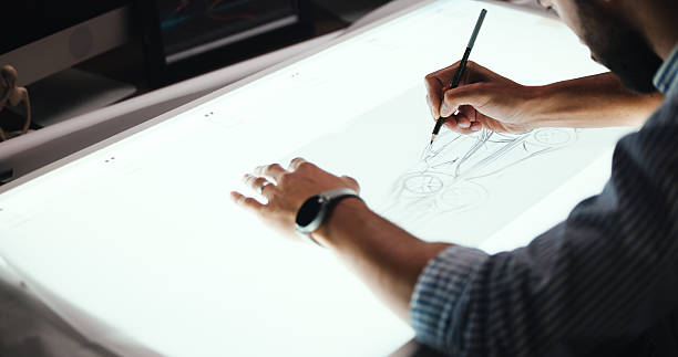 istock Man, hands and designer with drawing for car prototype, modeling or graphic design on light table. Male person, mechanical engineer or digital sketch with 2D vehicle, blueprint or automobile project 2213043464