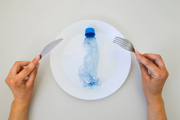 istock Symbolic Representation of Microplastic Pollution in Food  Plastic Bottle on Dinner Plate 2213046676