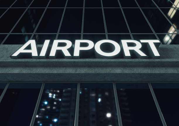 Generic signage above the entrance to a modern generic airport building made of exposed concrete and reflective glass at night time - 3D render