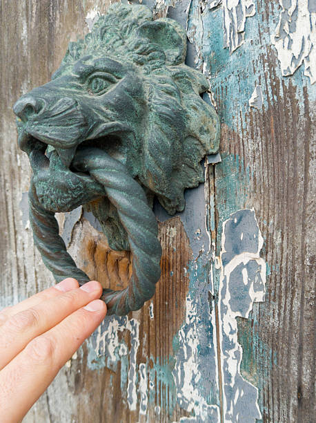 istock Hand knocking with lion head door knocker 2213047559