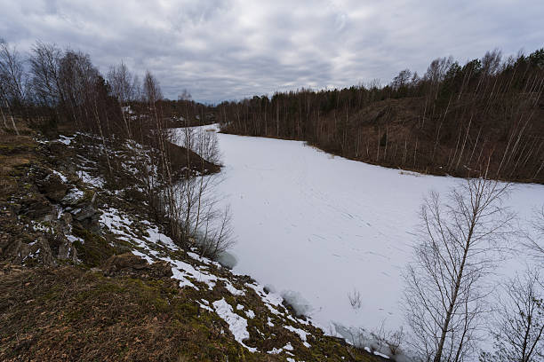istock Frozen water body, snow-covered banks, and trees under a dramatic cloudy sky. 2213048191