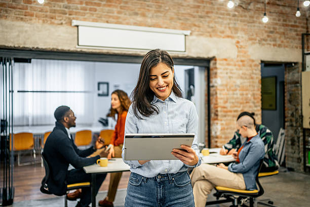 istock Young businesswoman using digital tablet in modern office with colleagues working in background 2213050762