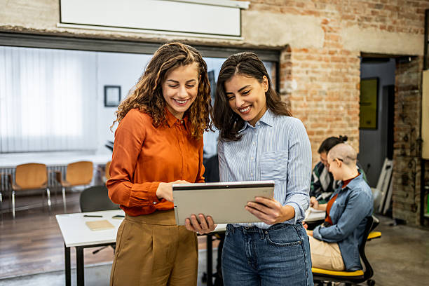 istock Two businesswomen smiling and using a digital tablet in the office 2213052212