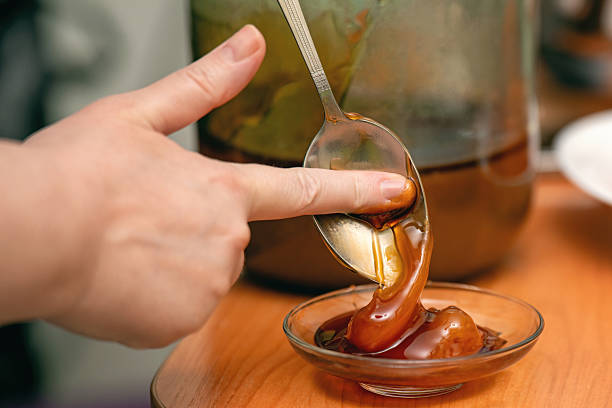 finger scoops honey from a spoon into a glass dish, capturing a natural and tactile food preparation moment