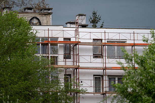 istock Apartment facade under renovation with scaffolding and green foliage 2213057841