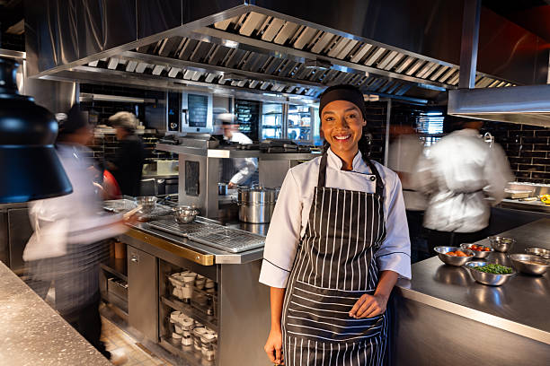 Portrait of a happy African American female chef working in a busy kitchen at a restaurant and smiling