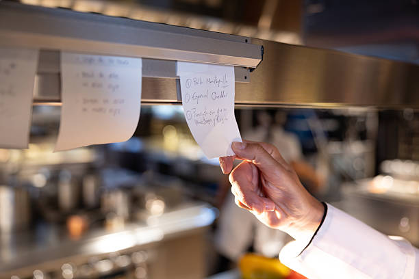 Close-up on a chef taking an order ticket in a commercial kitchen