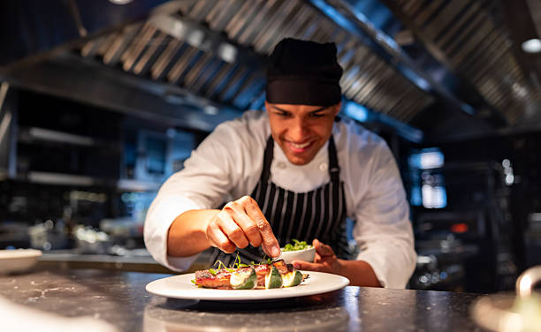 Chef decorating a plate while cooking in a commercial kitchen