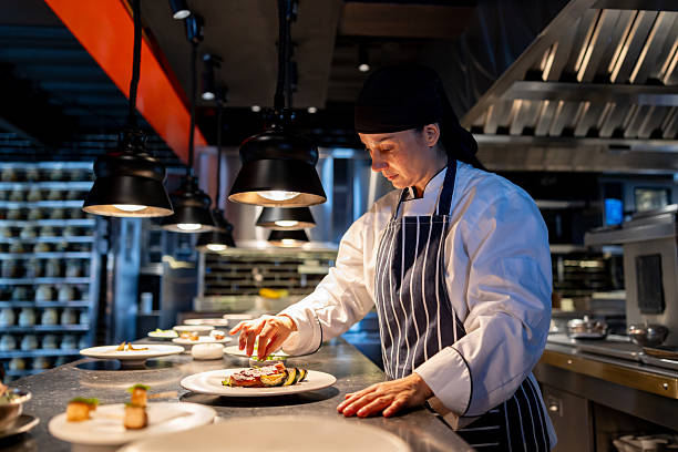 Cook decorating plates in a commercial kitchen at a restaurant stock photo