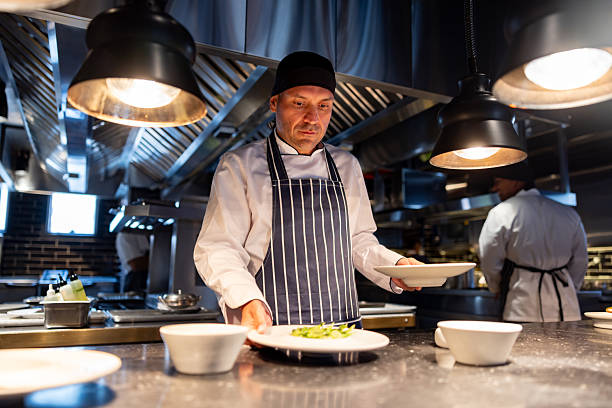 istock Cook serving a plate on the kitchen counter while working at a restaurant 2213060158