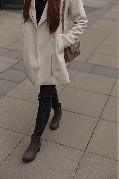 istock A woman in a white coat and brown boots walks down a sidewalk 2213060223