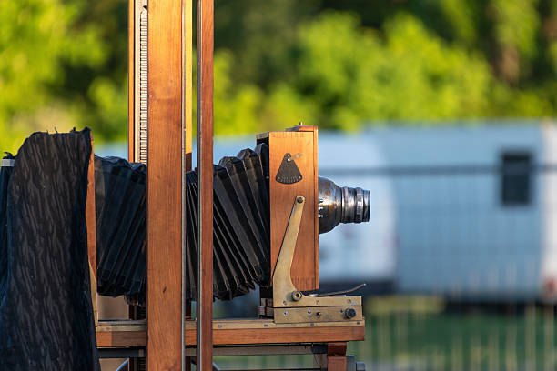 Vintage large format camera in outdoor setting with greenery.