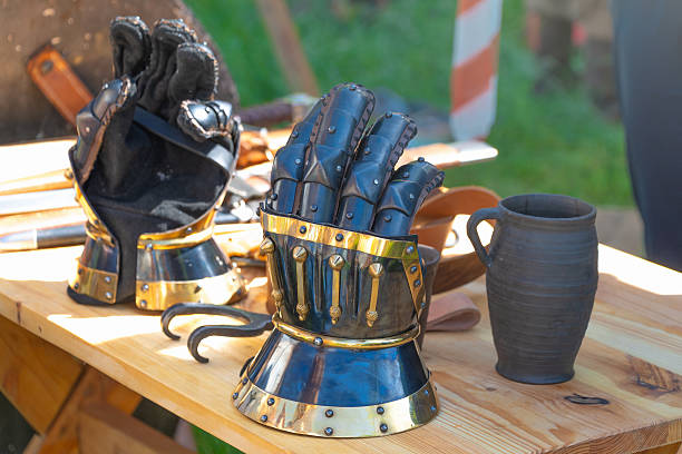 istock Medieval gauntlets on wooden table with ceramic jug in outdoor setting 2213061432