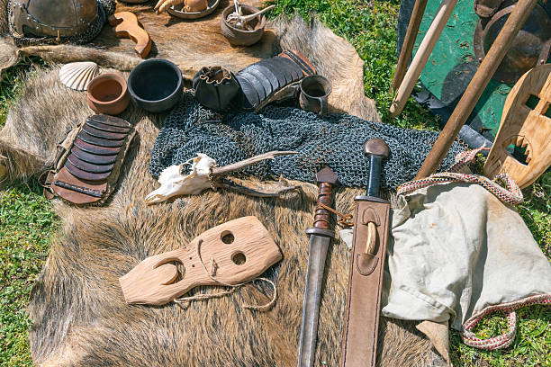 istock Medieval artifacts display: swords, masks, and armor on fur and grass 2213061452