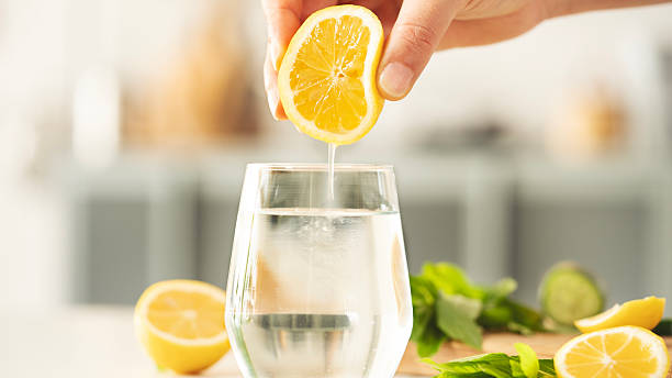 squeezing lemon into drinking water - citroen stockfoto's en -beelden