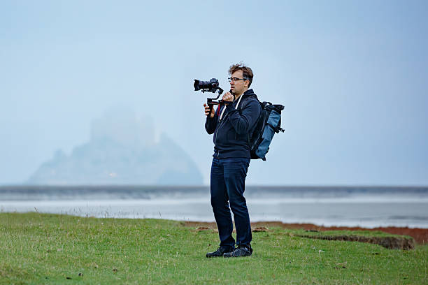 istock Man equipped with a camera films hazy Mont Saint Michel castle 2213063777